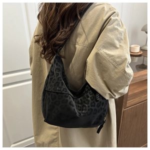 Detail of black leopard print hobo bag worn by model, showing nylon texture and strap