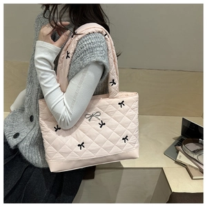 Detail van roze gewatteerde shopper met zwarte strikborduursels en zilveren hanger