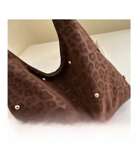 Dettaglio della borsa leopardata con borchie dorate e finitura in pelle scamosciata