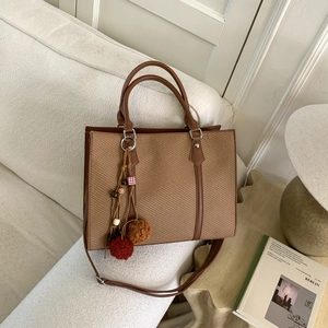 Retro braune Web-Tote-Bag mit Ledergriffen und Boho-Quaste auf einem gemütlichen Sofa