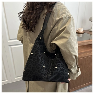 Detail of black leopard print hobo bag with gold studs on textured faux suede fabric