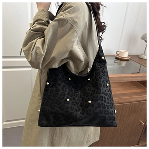 Dettaglio della borsa tote in pelle scamosciata leopardata con borchie su trench kaki