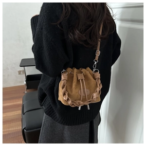 Dettaglio borsa a secchiello vintage in pelle scamosciata marrone con chiusura a coulisse su modella