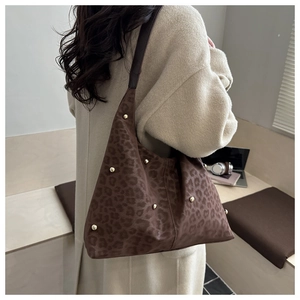Dettaglio dei rivetti dorati su una borsa tote scamosciata marrone con stampa leopardata