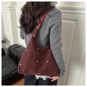 Dettaglio borsa tote bordeaux con stampa leopardata e borchie dorate decorative
