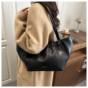 Detail shot of a black pleated cloud bag with a gold logo on a slim shoulder strap