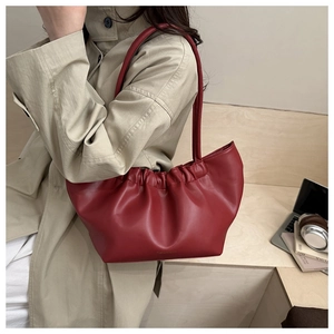Detail view of burgundy ruched PU leather bag on wooden stairs with modern props