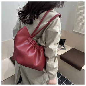 Détail du sac à bandoulière en cuir rouge foncé avec plis élégants et gaufrage chic