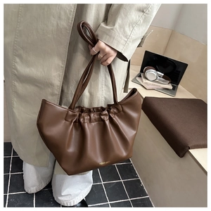 Brown pleated cloud tote bag with gold lettering shown in a stylish commuting setup