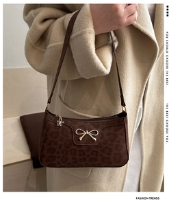 Detail of leopard print underarm bag with gold bow clasp and floral zipper puller