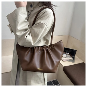 Detail of coffee brown pleated cloud bag on model showing soft leather texture