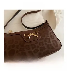 Close-up of leopard print shoulder bag featuring a gold bow clasp and petal-shaped zipper