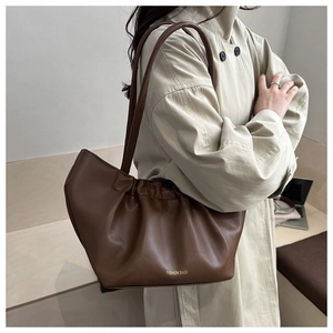 Detail of dark brown ruched tote bag with thin straps and gold logo lettering