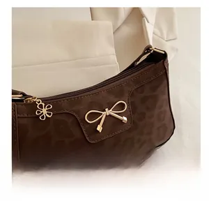 Detail view of leopard print hobo bag with gold bow clasp and floral zipper pull