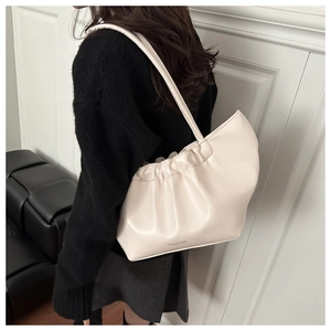 Detailed close-up of beige pleated shoulder tote bag with minimalist logo text