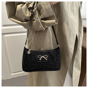 Detail of black bow shoulder bag with leopard print on a khaki trench coat model