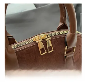 Detail van gladde gouden dubbele ritsen en stiksel op een donkerbruine vintage tas