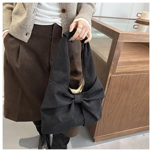 Détail du sac cabas en velours côtelé noir avec un grand nœud décoratif et texture côtelée