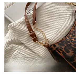 Dettaglio borsa baguette leopardata con tracolla in pelle marrone e fibbia in metallo oro