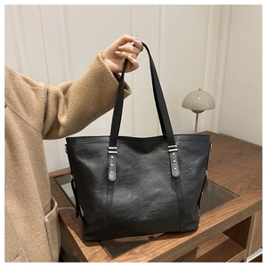 Close-up of black leather tote bag featuring silver star rivet detail and soft texture
