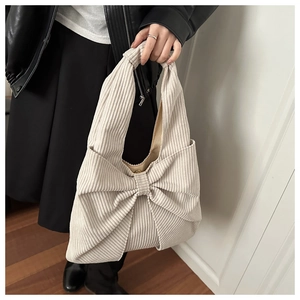 Detailed texture view of the cream corduroy tote bag with large decorative bow