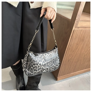 Dettaglio della borsa baguette leopardata con manico in pelle nera e catena dorata