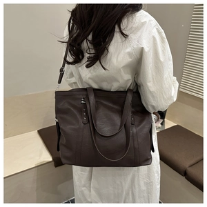 Detail of vintage brown tote bag with pebble leather texture and rivet accents