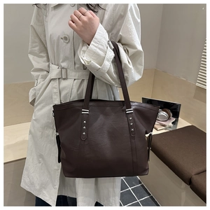 Close-up of dark brown tote bag with silver star rivets and premium litchi grain texture