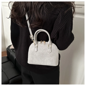 Detail van klaverreliëf op een retro minimalistische schelptas met metalen rits