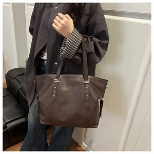 Detailed shot of dark brown tote bag featuring silver star rivets and soft leather texture