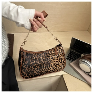 Dettaglio borsa a mezzaluna leopardata con bordo marrone e tracolla a catena dorata
