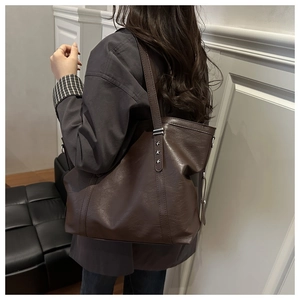 Detail of dark brown tote bag showing soft textured leather and star rivet hardware