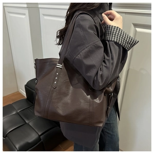 Detail of dark brown faux leather tote bag with silver star rivets and shoulder straps