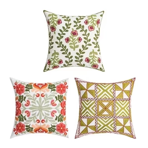 Ensemble de housses de coussin brodées à motifs floraux et géométriques sur fond blanc
