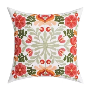 Détail de la broderie florale sur une housse de coussin de canapé en tissu blanc doux