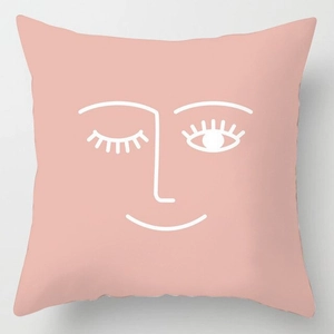 Dettaglio della federa rosa in peluche con design minimalista del viso a linee bianche