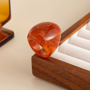 Detail of amber resin ring with marble texture on walnut jewelry display box