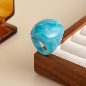 Macro detail of sky blue resin ring with white marble texture on vintage wooden box