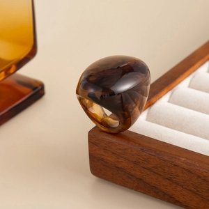 Detailed close-up of amber resin ring displayed on a solid wood jewelry box edge