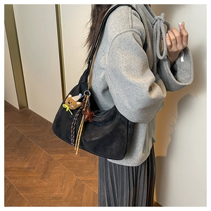 Detail of black suede tote bag featuring cute bear charm and star pendant accessory