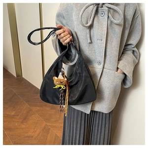 Detail of black nylon crescent hobo bag with cute brown bear charm and colorful tassels