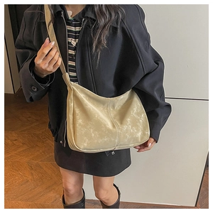 Detail of vintage beige crossbody bag with cracked texture shown on model for daily wear