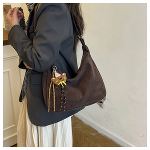 Side view of dark brown faux suede shoulder bag featuring a cute cartoon bear charm