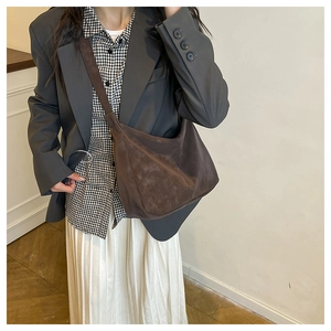 Detail view of deep brown suede crossbody bag styled with a minimalist autumn outfit