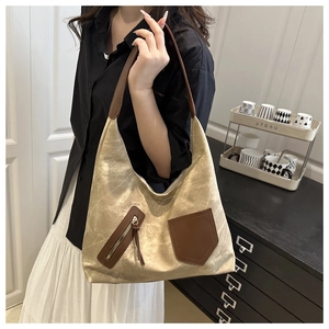 Detail of a large gold tote bag with a metallic finish and brown leather straps