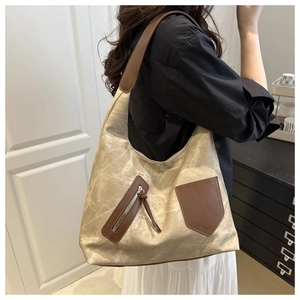 Close-up of metallic champagne tote bag with brown leather details and side zipper