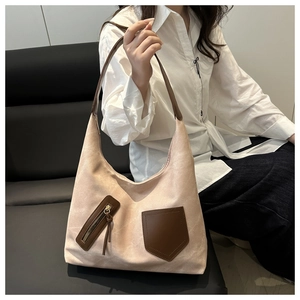 Detail view of large beige canvas tote bag with brown leather handles and contrast pockets