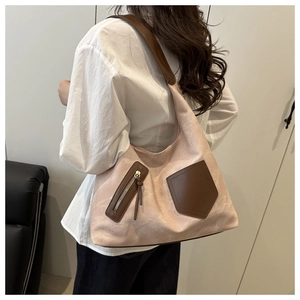 Detail of a large pink suede tote bag with brown leather pocket and long tassels