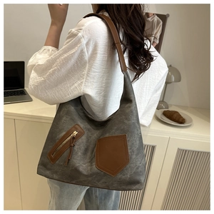 Close-up of a large canvas tote bag with leather straps and front pockets in a cafe setting