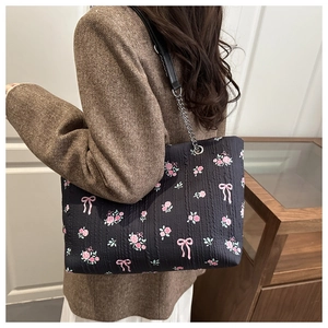Close-up of floral tote bag with textured fabric, rose prints, and metal chain strap
